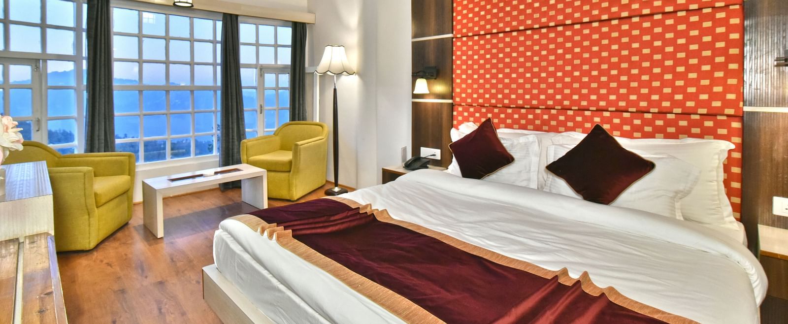 A bedroom with a seating area by the window, offering a mountain view at DLS Hillcrest Resort, Shimla.